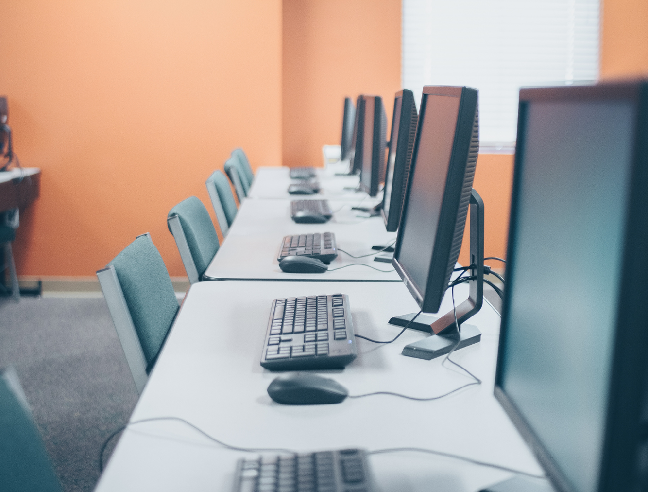 Computer screens in office side by side along a long desk