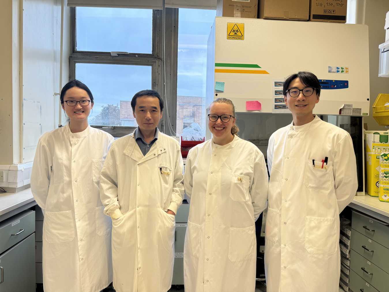 Four scientists in white lab coats, Jian and Katie in the middle