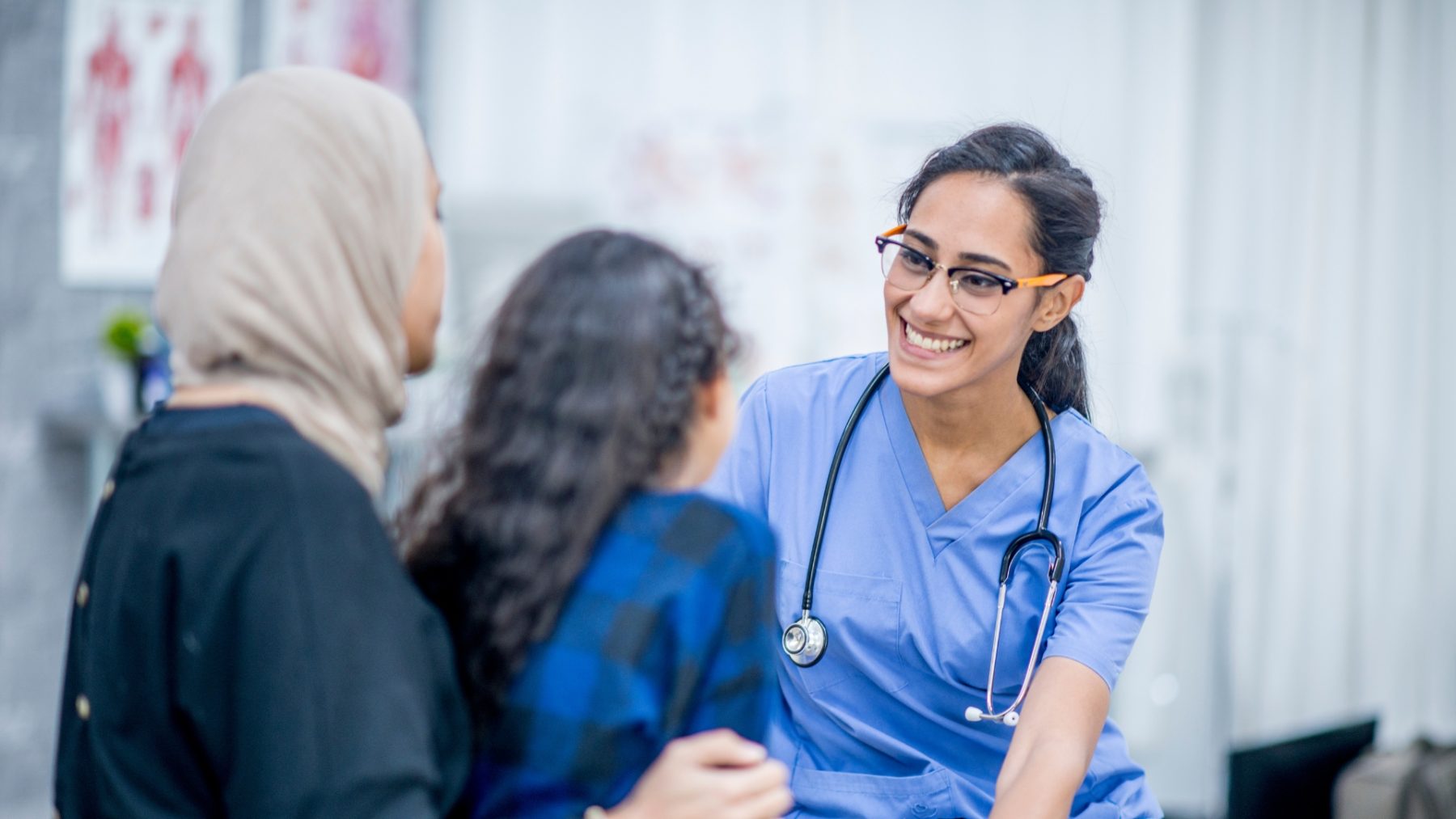 Ophthalmologist talks to young patient and her mother in hospital room