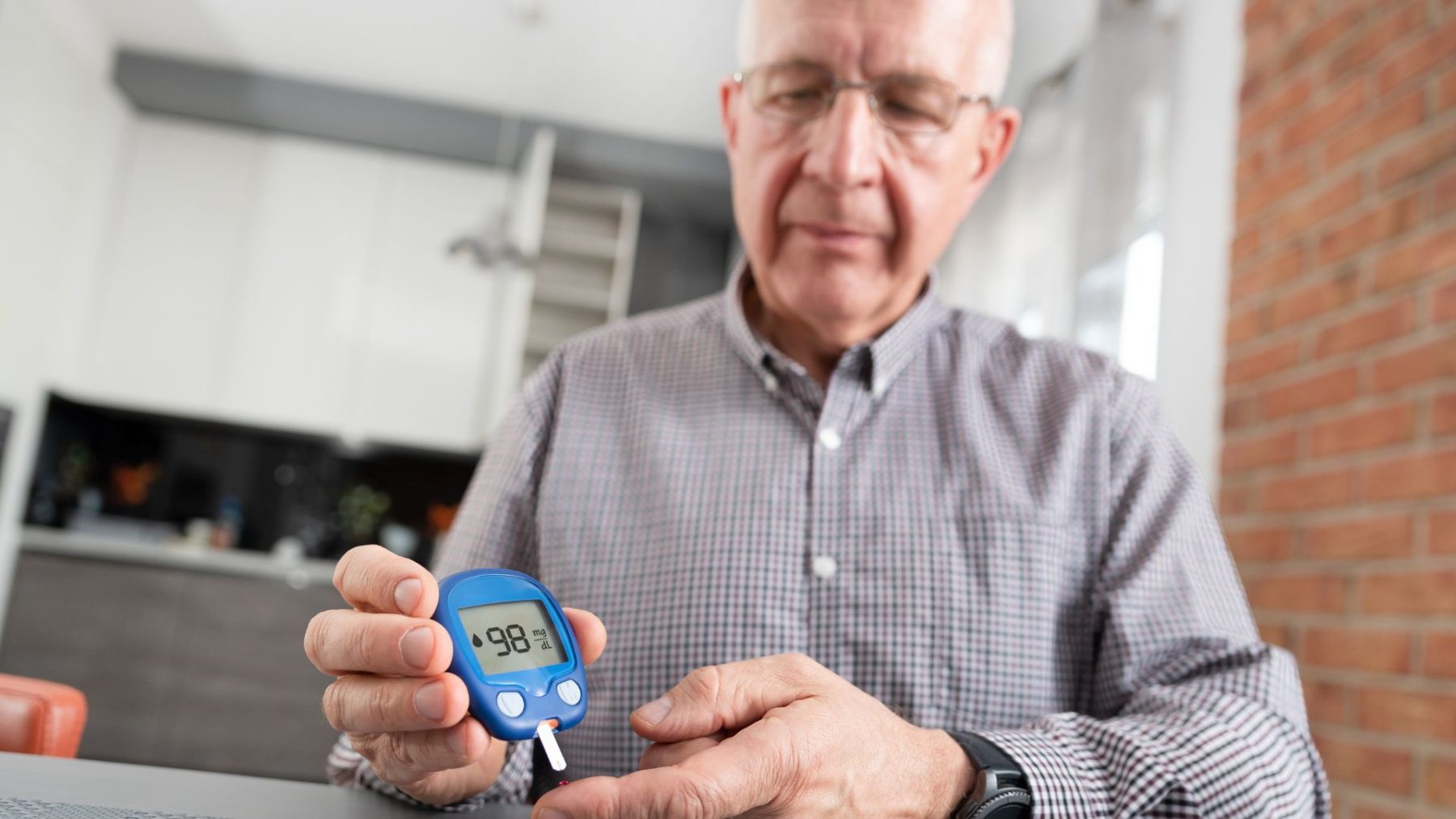 Man wearing a shirt and glasses checking his blood sugar level