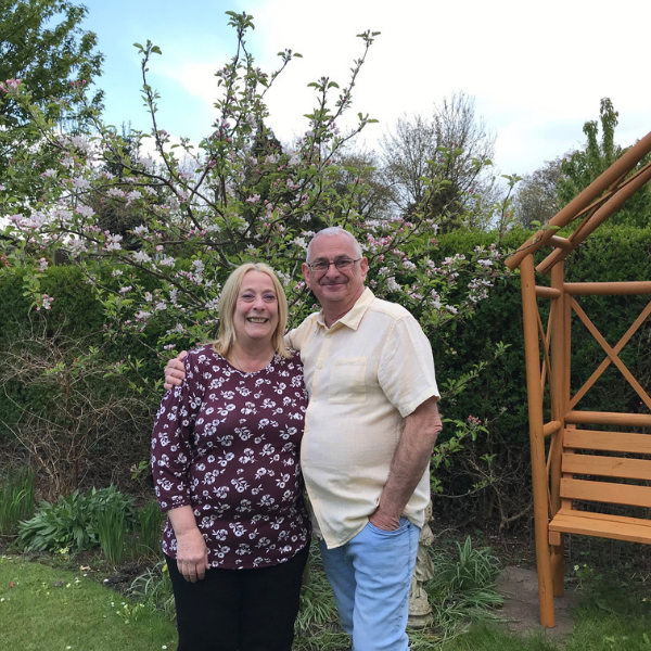 Annie (left) and Graham (right) standing in garden embracing