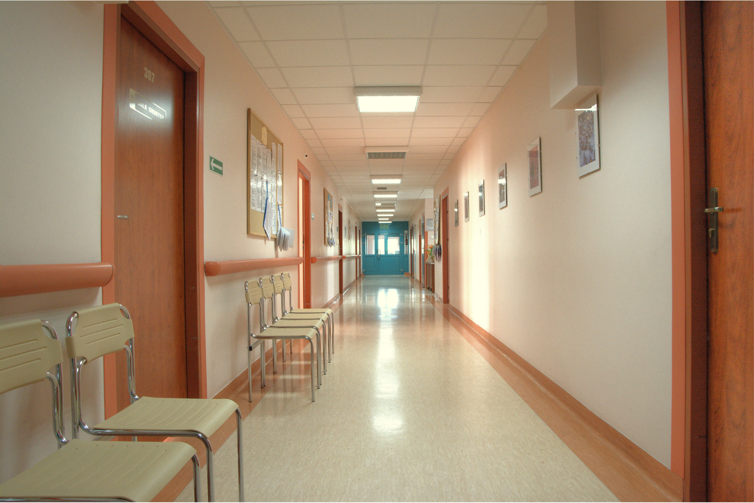 Hospital corridor with blue double doors at the end