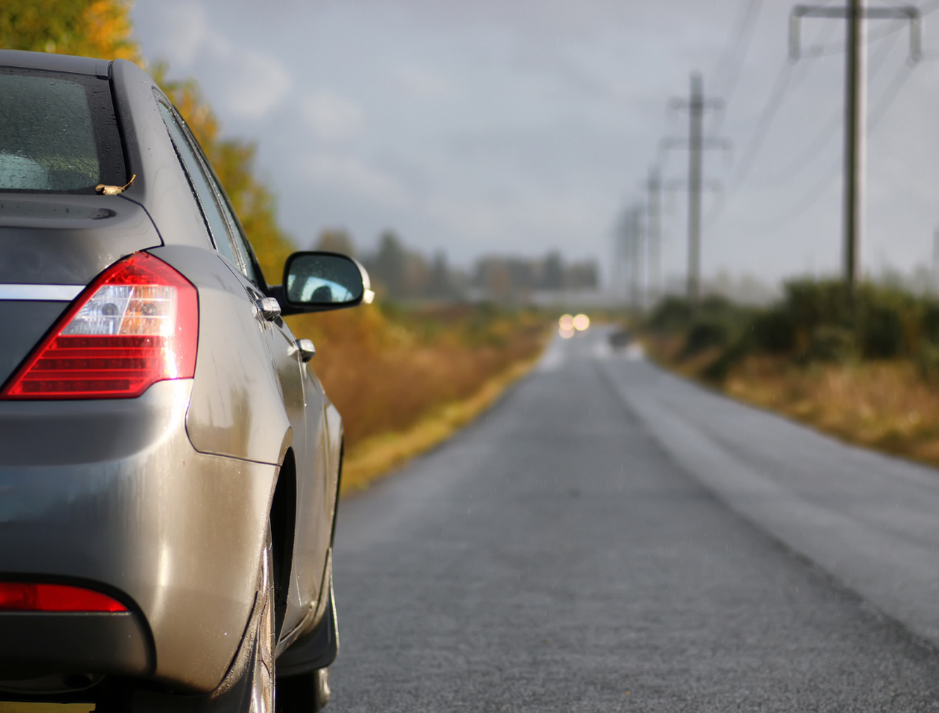 Car parked on country road with cars approaching in distance