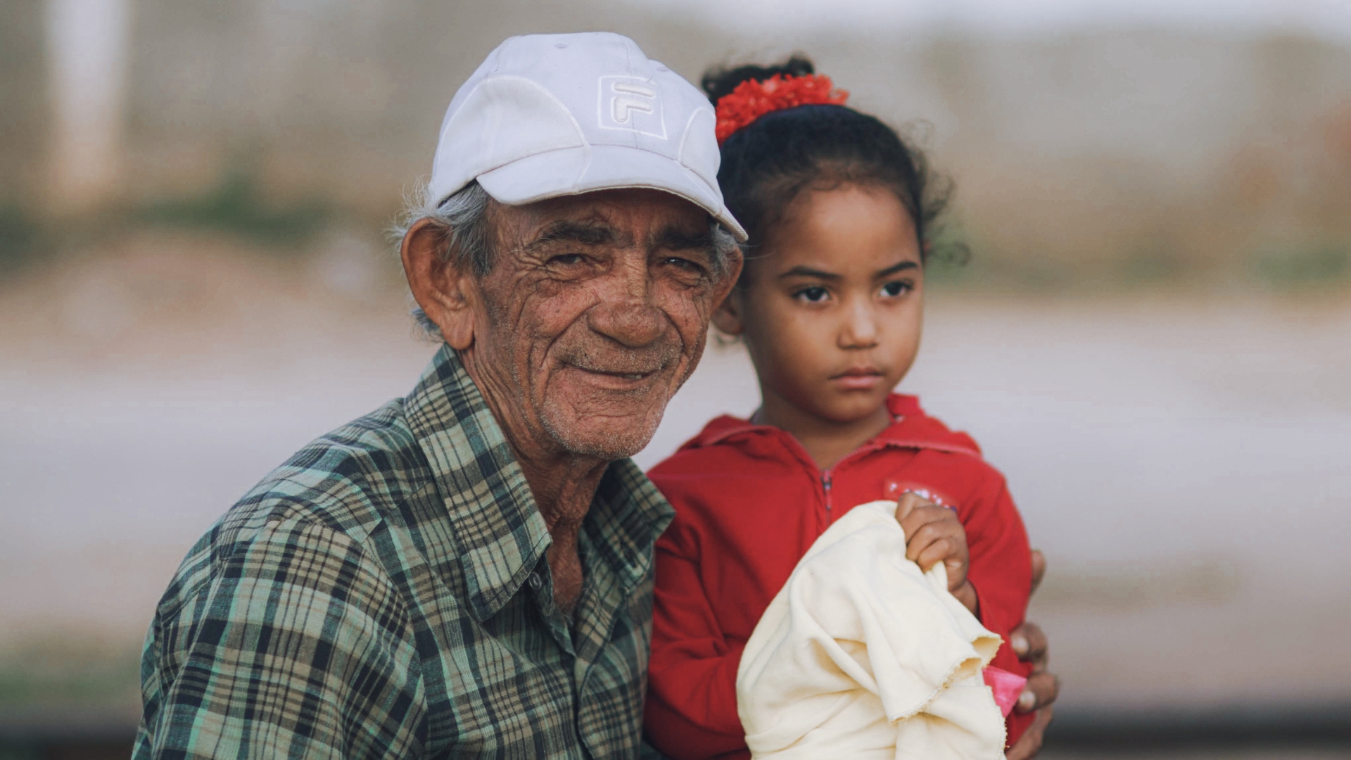 Grandad wearing hat beside granddaughter smiling