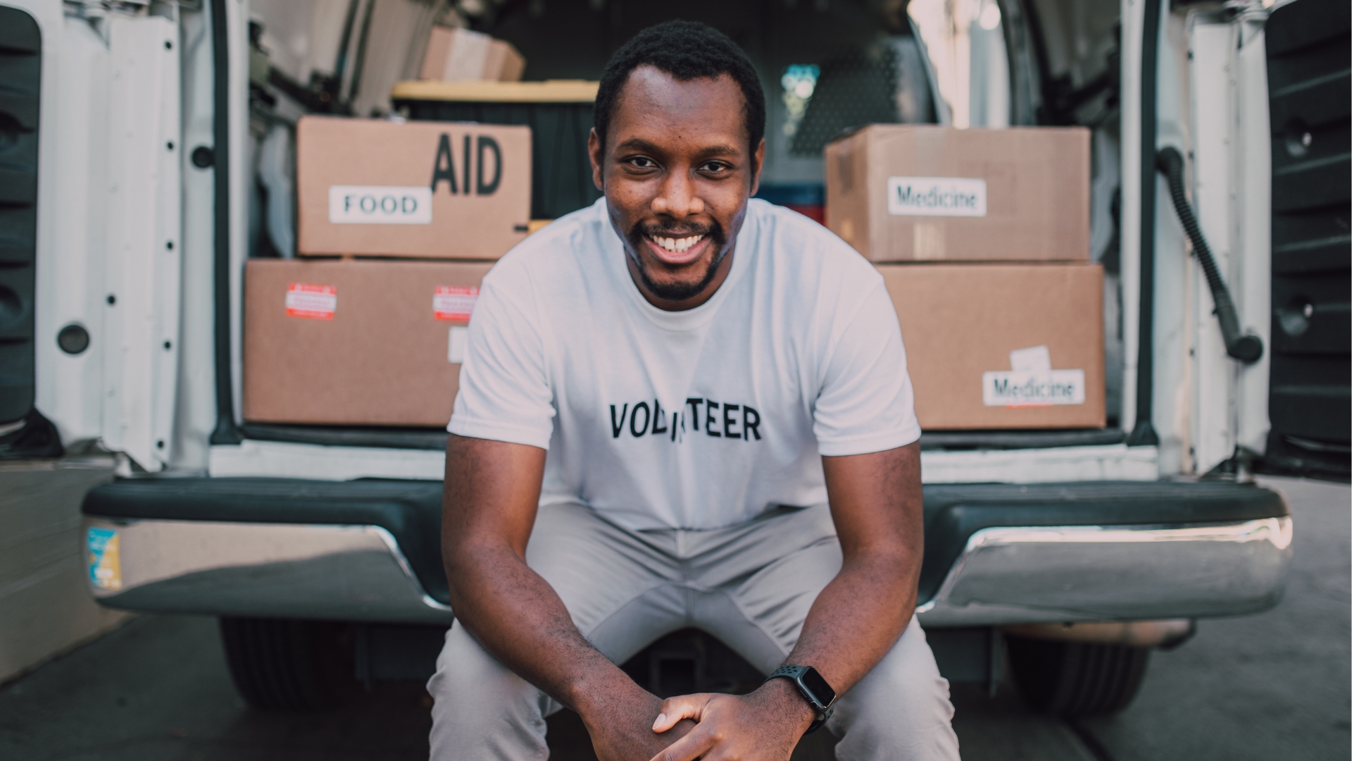 Volunteer sat in front of truck with boxes of aid relief