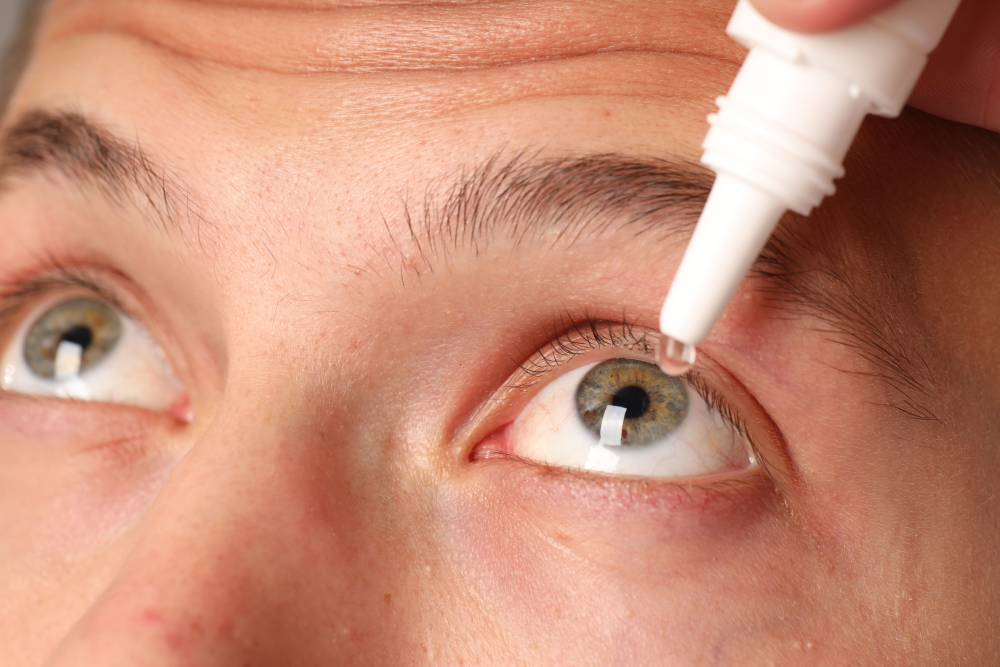 Person applying eye drops to their eye.
