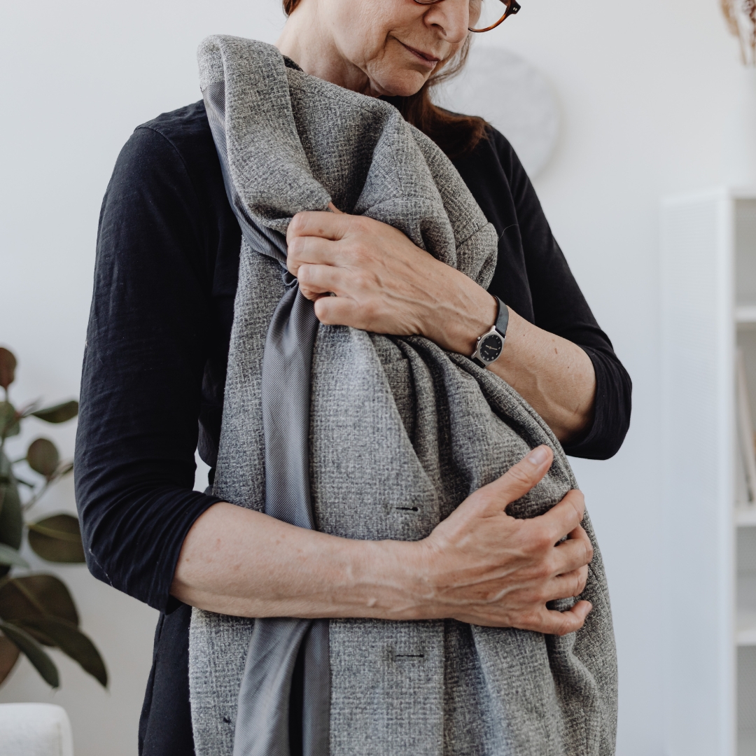 Women wearing glasses holding a man's jacket in her arms