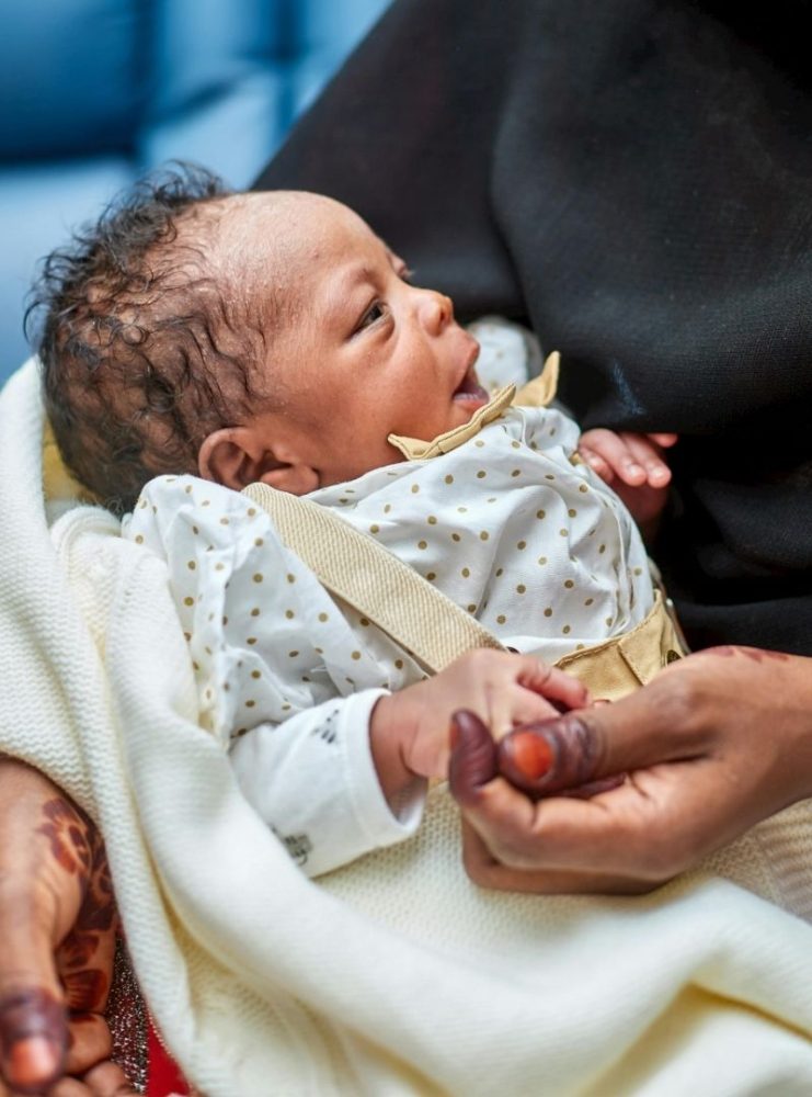 Newborn baby being held by an adult.