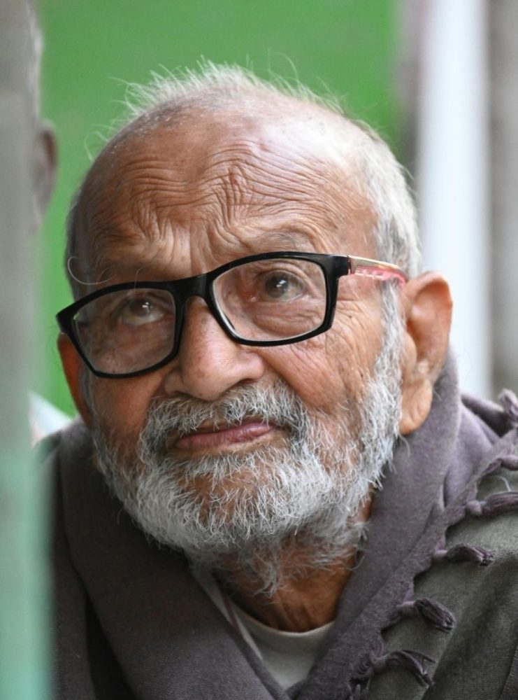 Elderly man wearing a shawl and glasses.