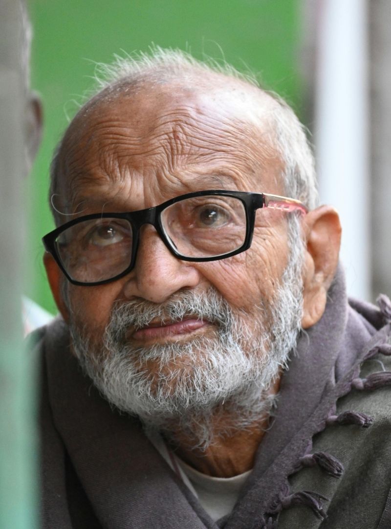 Elderly man wearing a shawl and glasses.