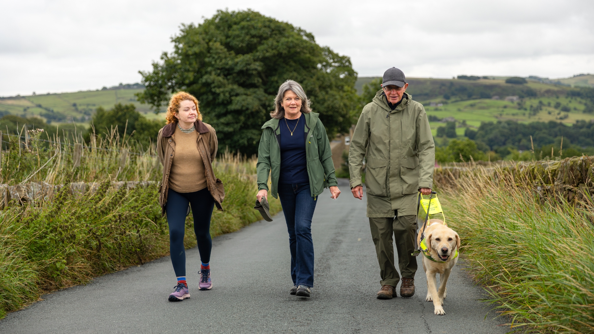 Three people walking with a guide dog.